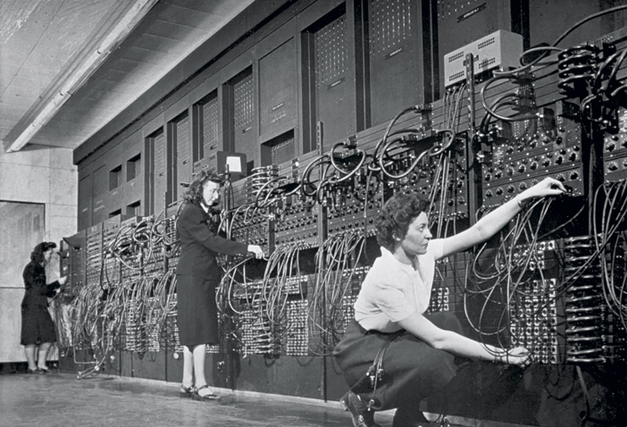 ca. 1940s --- Computer operators program ENIAC, the first electronic digital computer, by plugging and unplugging cables and adjusting switches. | Location: Mid-Atlantic USA.  --- Image by © CORBIS